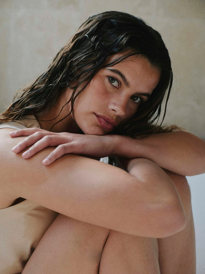 Post-shower contemplative portrait, warm natural light, evoking the calm skin-care ritual that good sleepwear should support for sensitive skin