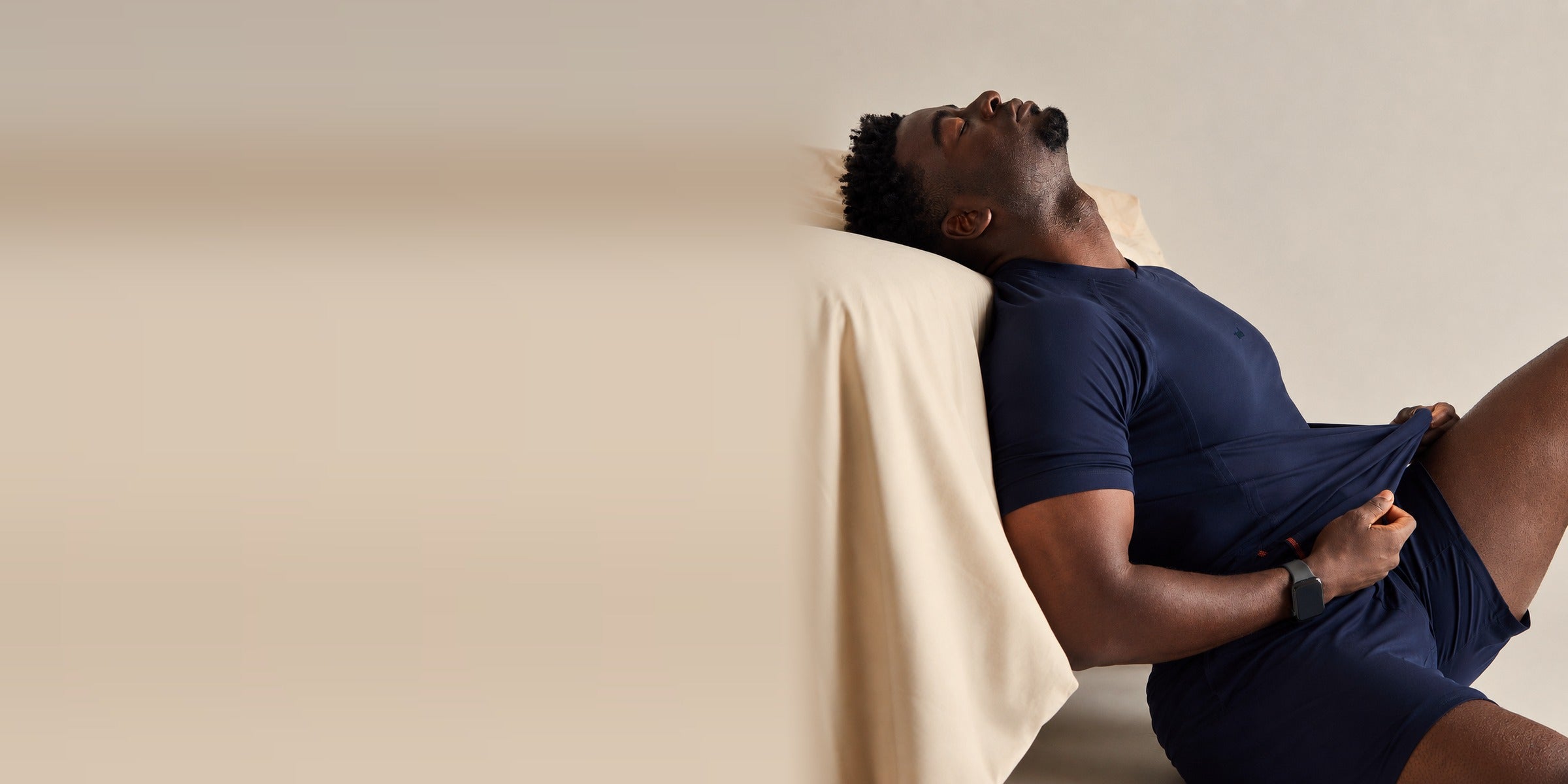 Man reclining against a cream pillow in a navy Zed short-sleeve sleep set